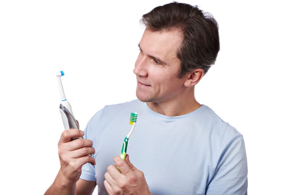 Man chooses between electric and manual toothbrush
